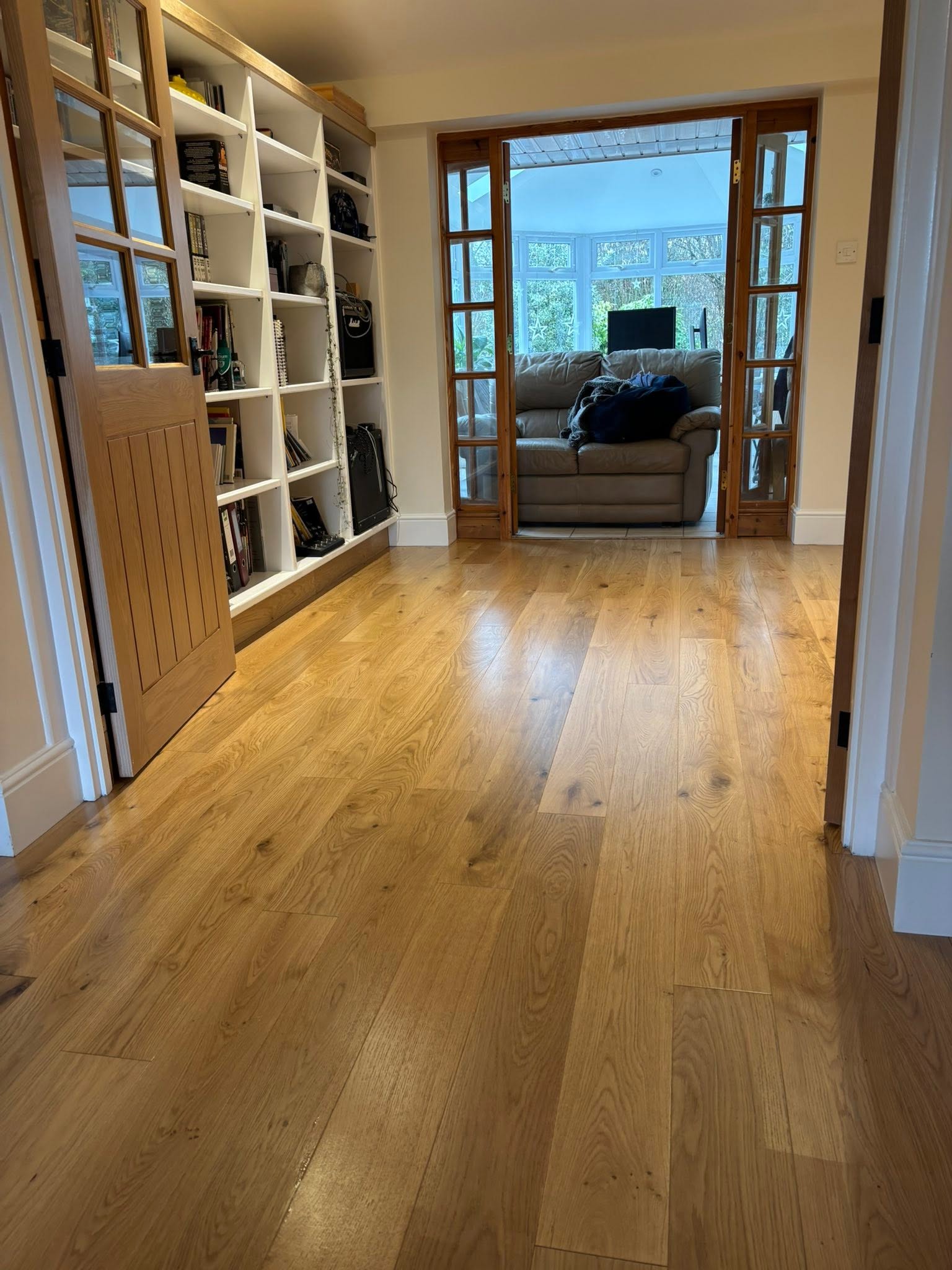 Bright modern living space with wooden flooring and shelving